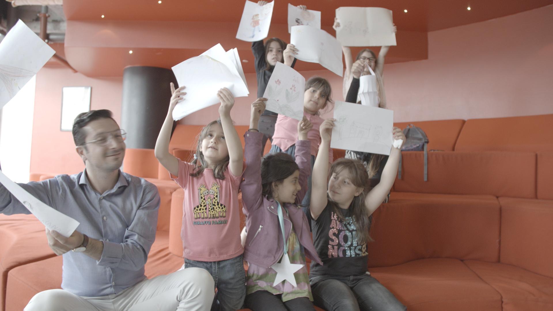 Children and facilitators raising drawings during a Hero To Be activity